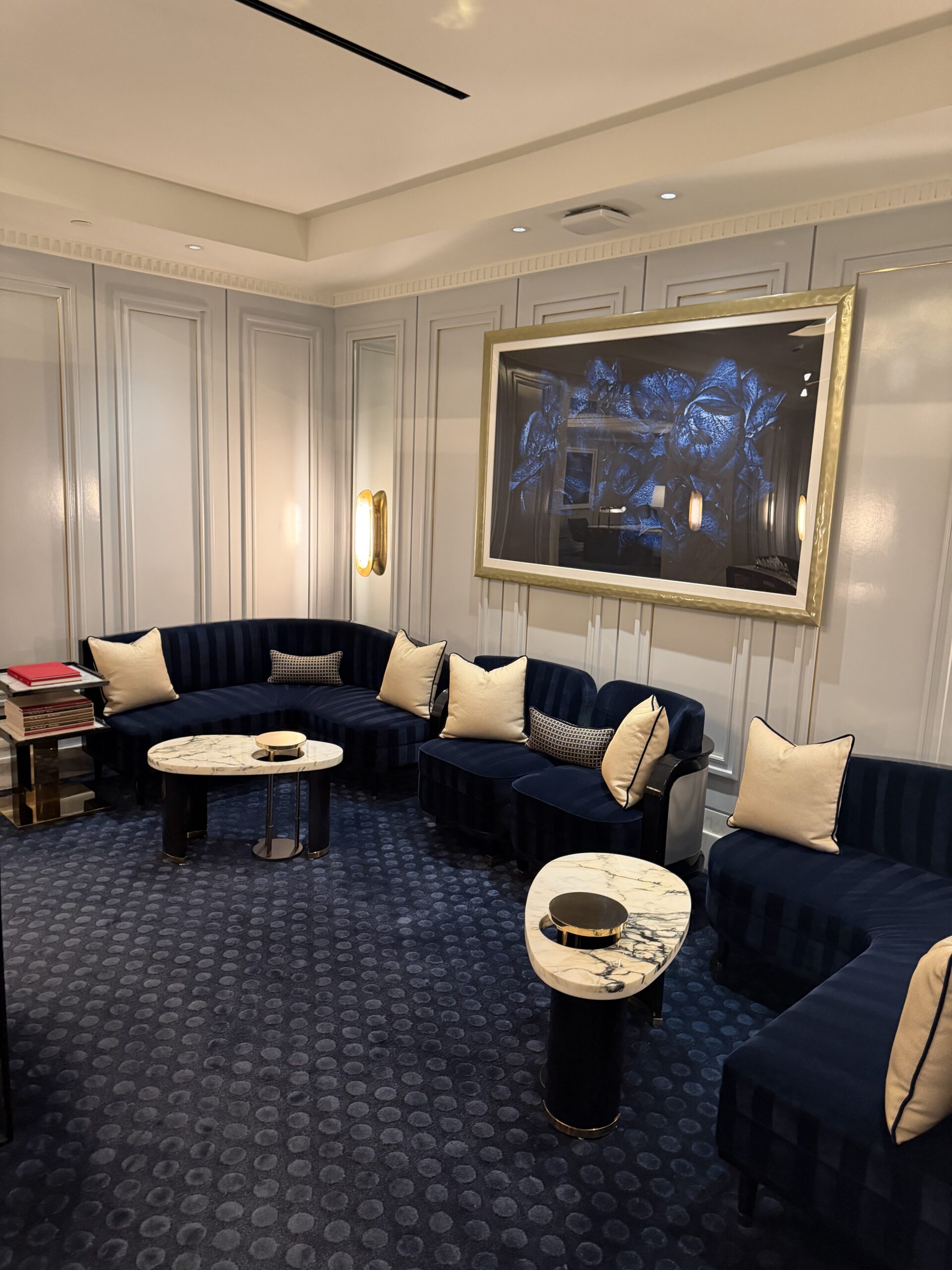 Lounge seating area with navy velvet sofas and gold framed art at Fontainebleau Las Vegas